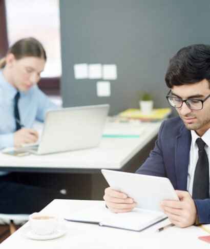 Financial Managers at Work Concentrated young managers in formalwear preparing financial accounts on computers while sitting at modern open plan office